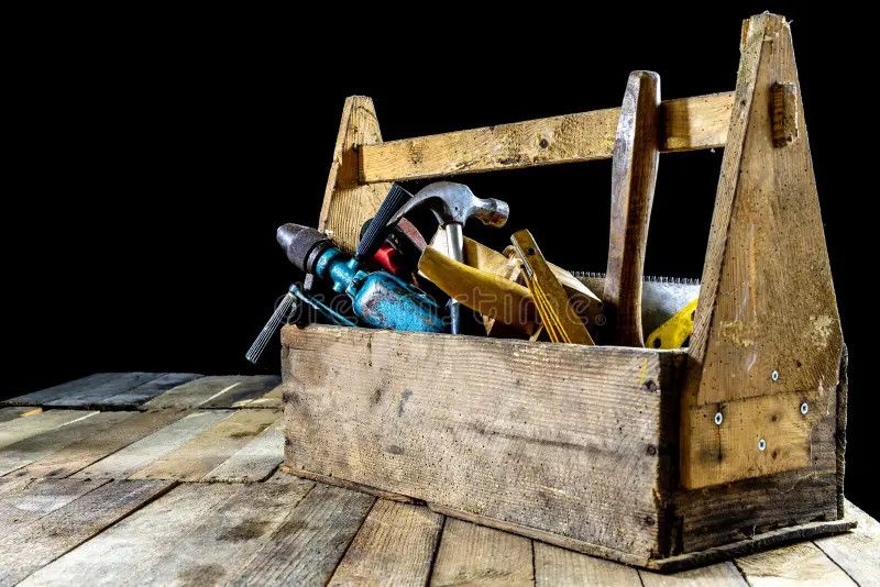 Alte hölzerne Werkzeugkiste mit Hammer, Bohrmaschine und Massstab